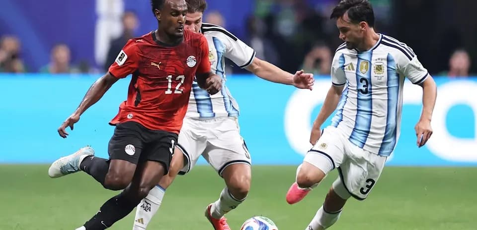Egyptian player dribbling past two Argentine defenders
