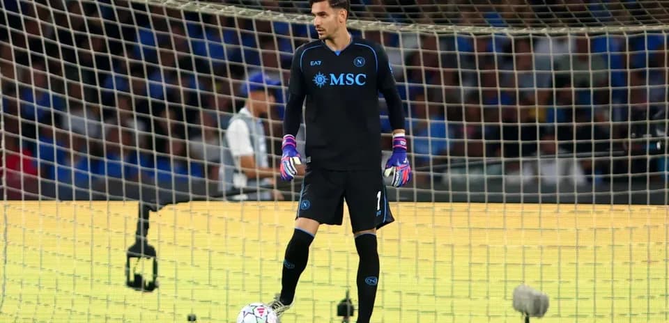 Goalkeeper in black uniform standing near goalpost
