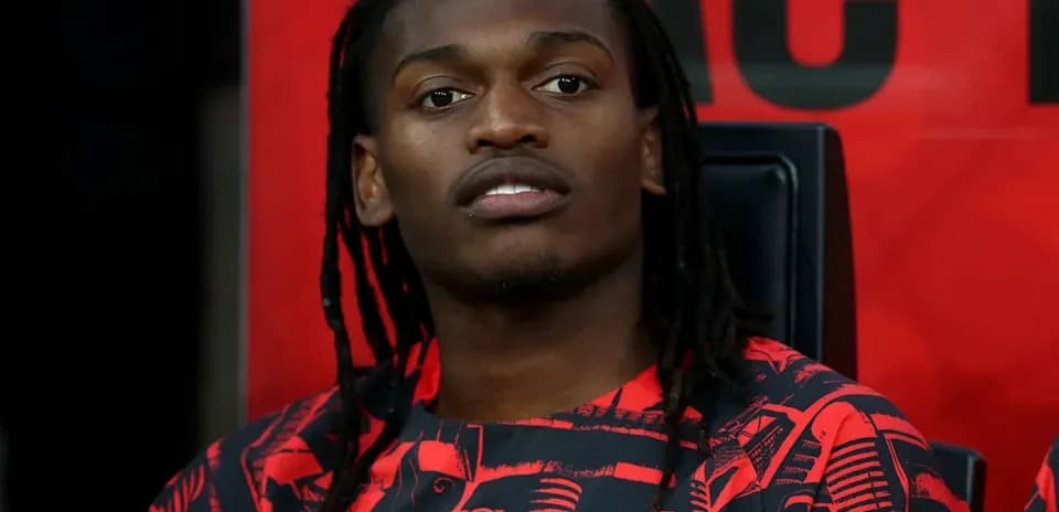Player sitting on bench wearing AC Milan jersey