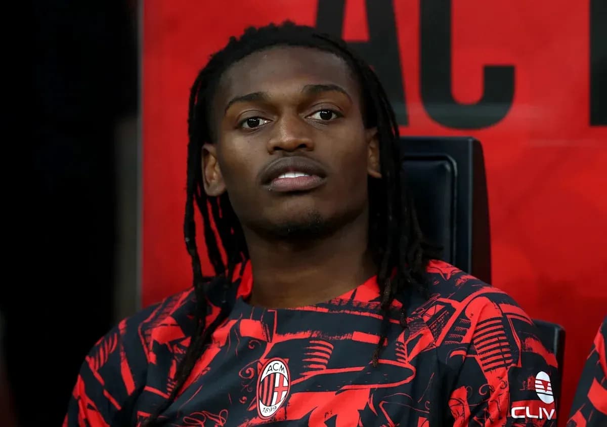 Player sitting on bench wearing AC Milan jersey