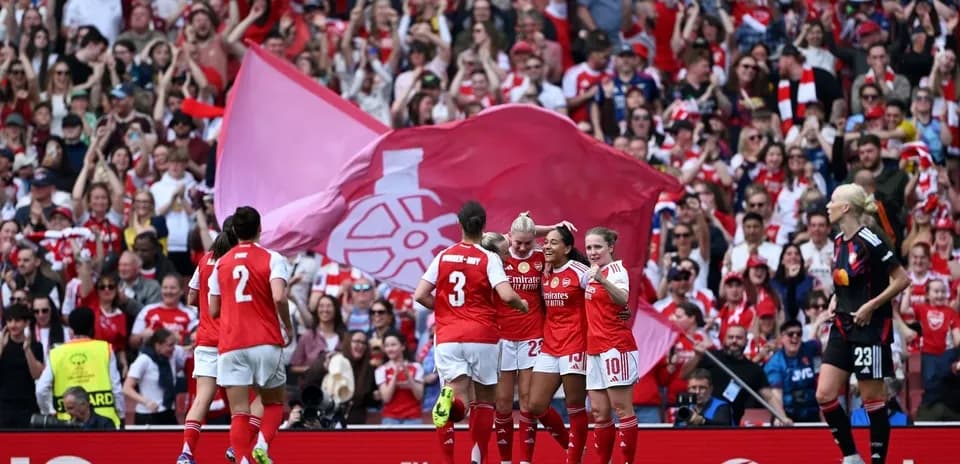 Arsenal women celebrating a goal with fans in background
