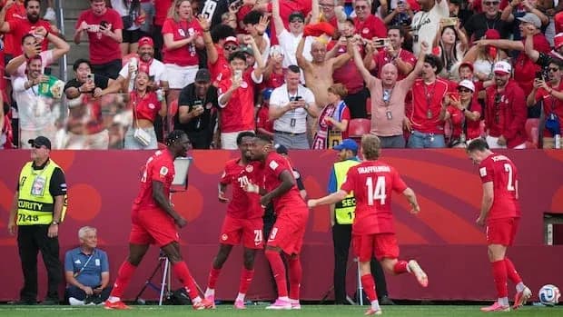 Players celebrating a goal with fans in background