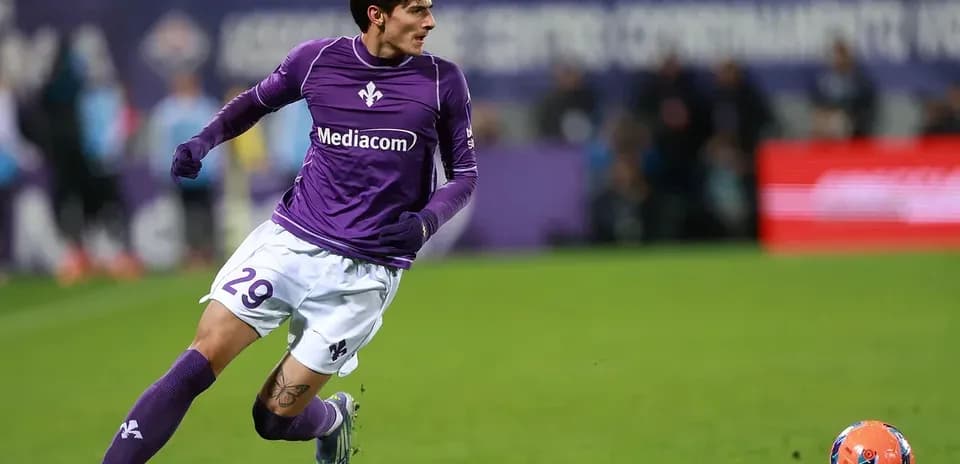 Player in purple kit running towards ball on field