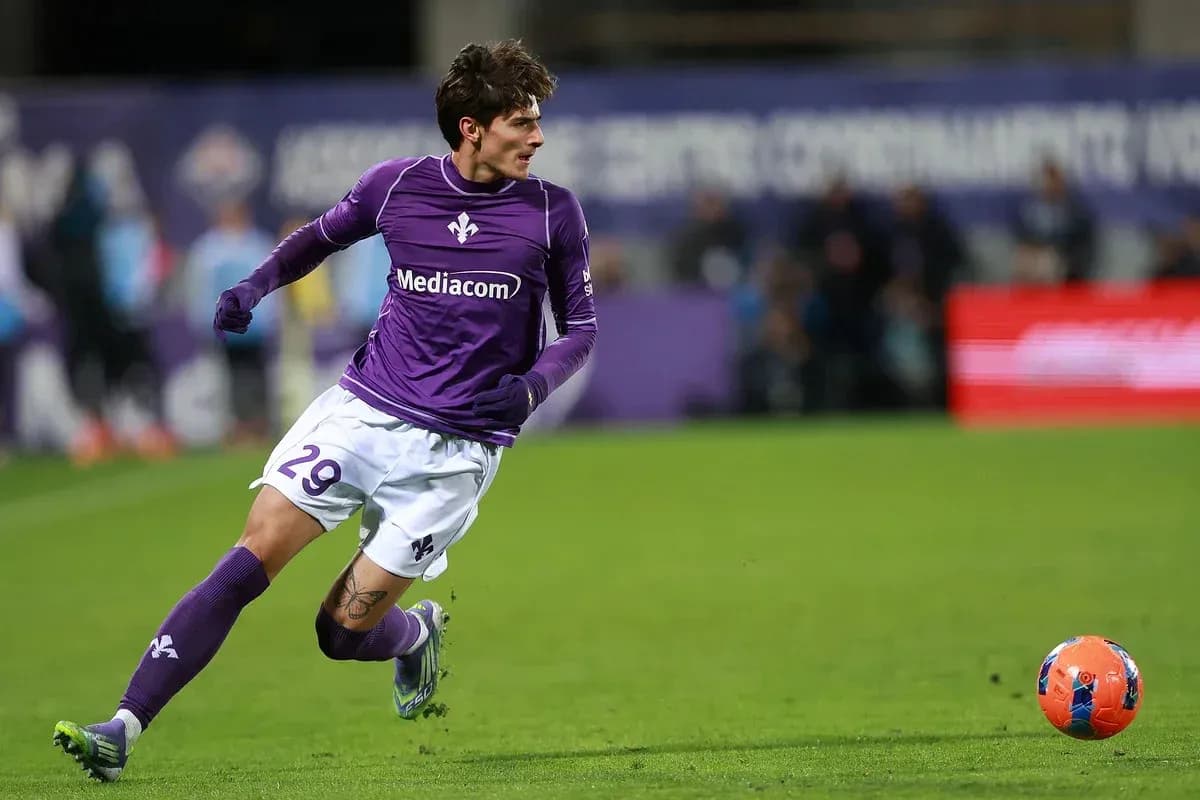 Player in purple kit running towards ball on field