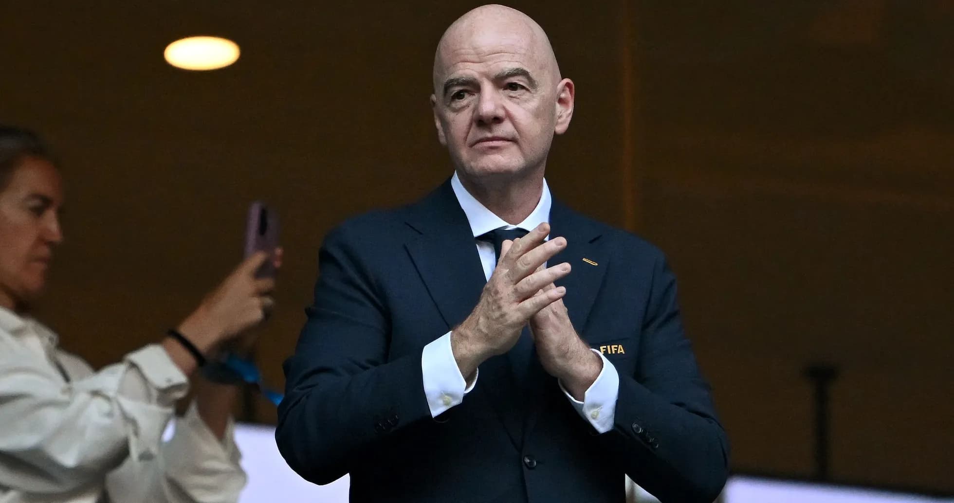 FIFA official clapping in a stadium box