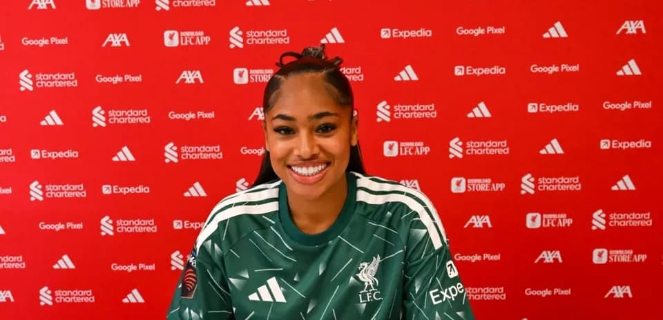 Player smiling during press conference with Liverpool backdrop