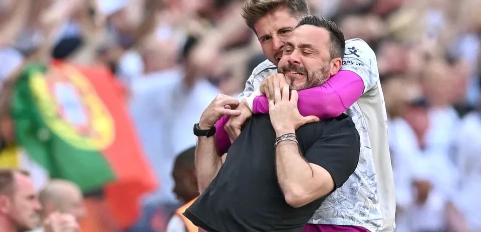 Two coaches celebrating in a crowd during match