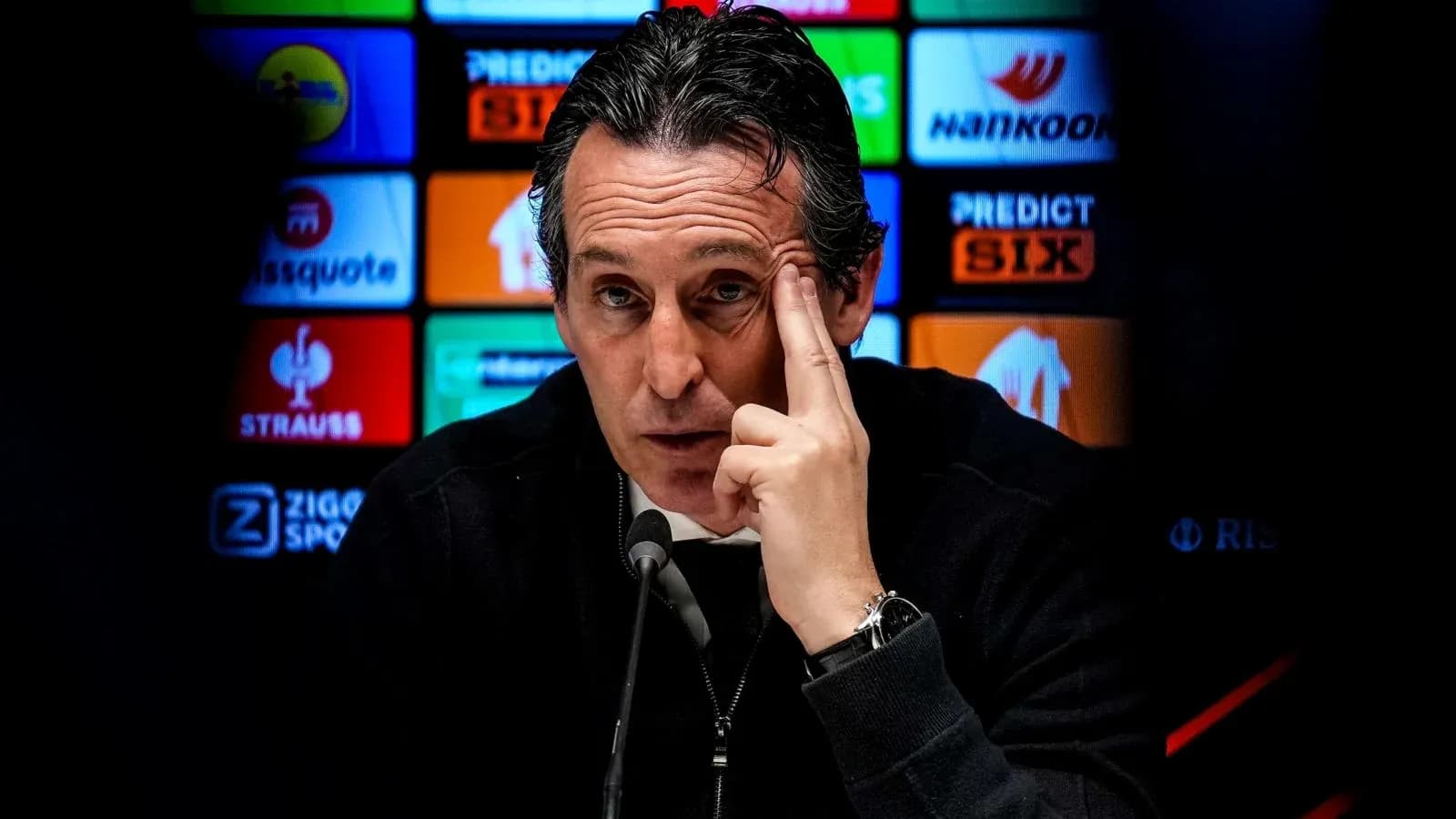 Manager speaking at press conference with logos behind