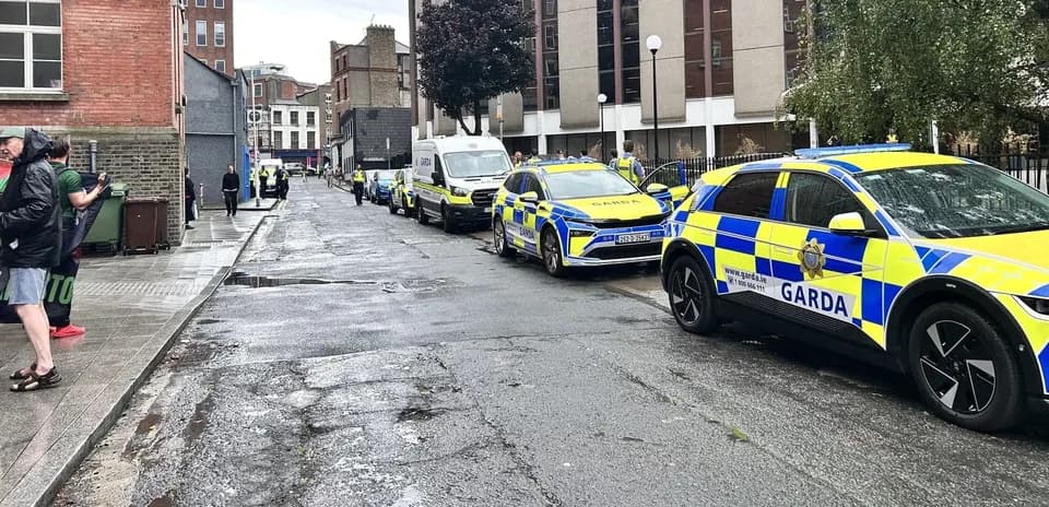 Garda vehicles parked along a wet street