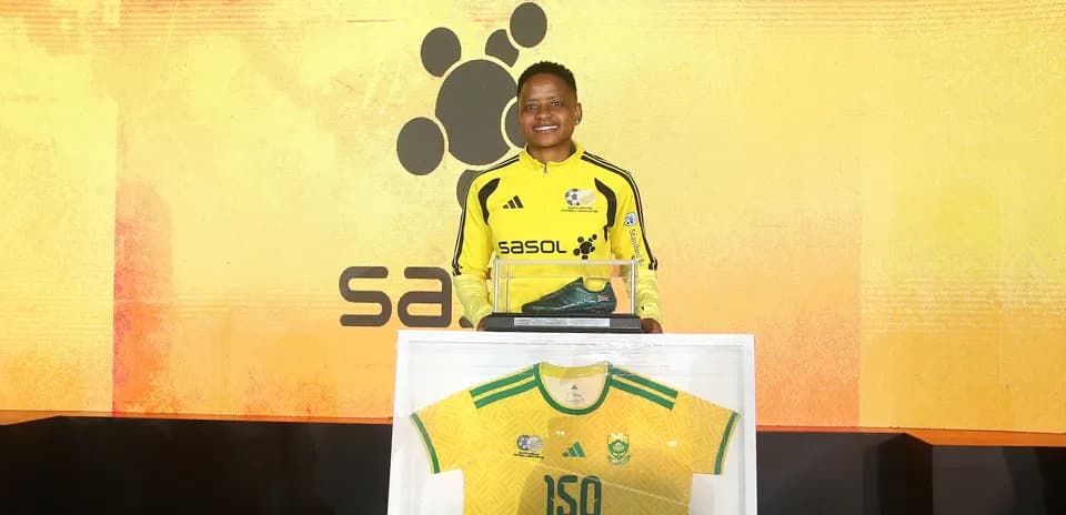 Player holding award with jersey and boots displayed