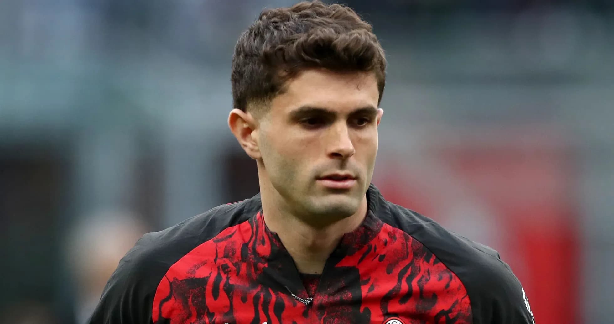 Player in red and black jersey walking on pitch
