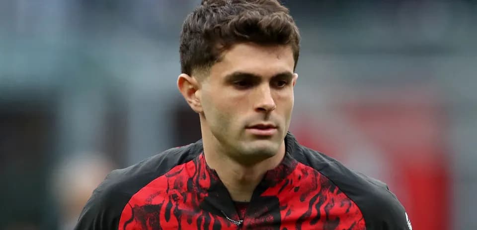 Player in red and black jersey walking on pitch
