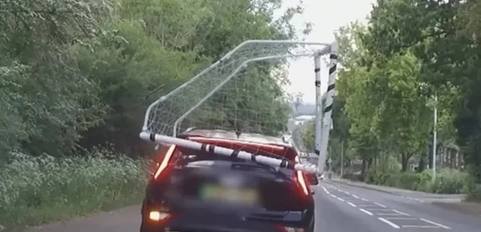Car transporting a soccer goal on a road