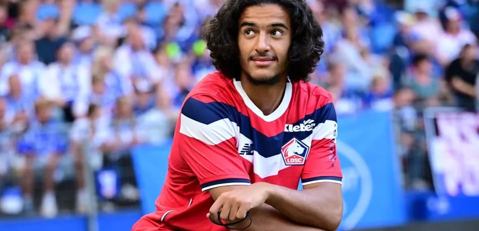 Player in LOSC Lille jersey sitting on field