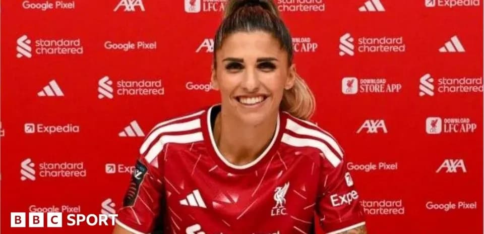 Player smiling in Liverpool jersey at press conference