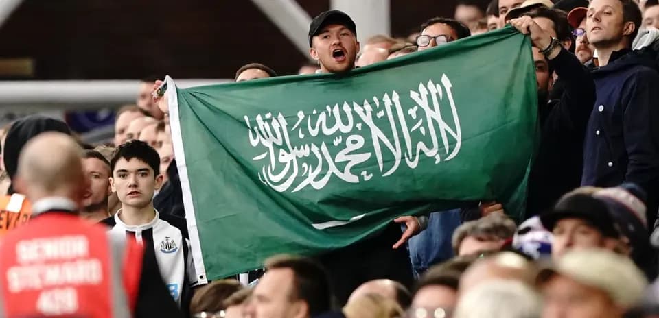 Fans holding Saudi Arabian flag in the stands
