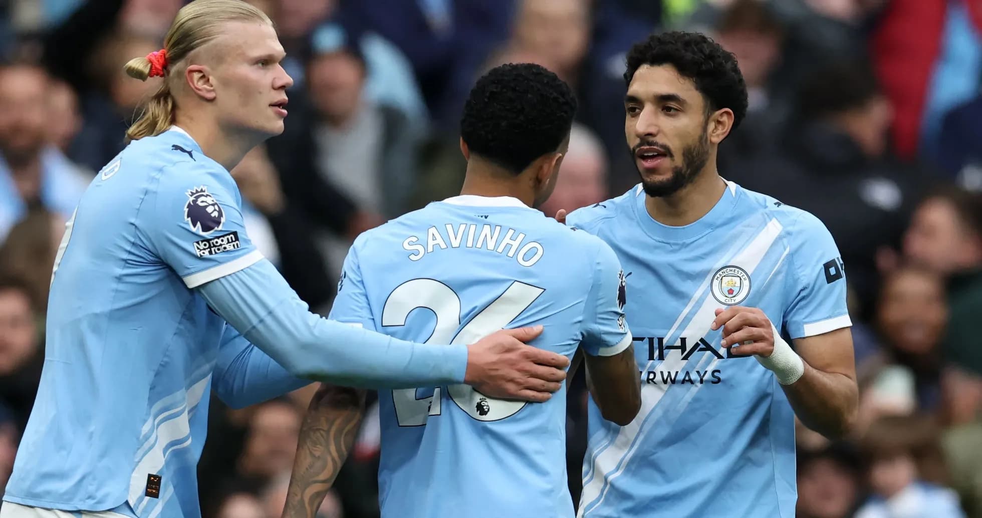 Three Manchester City players celebrating on the pitch