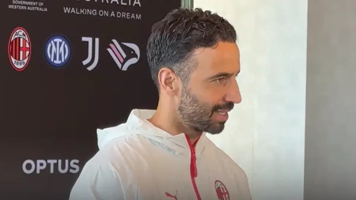 Man speaking at press conference with club logos