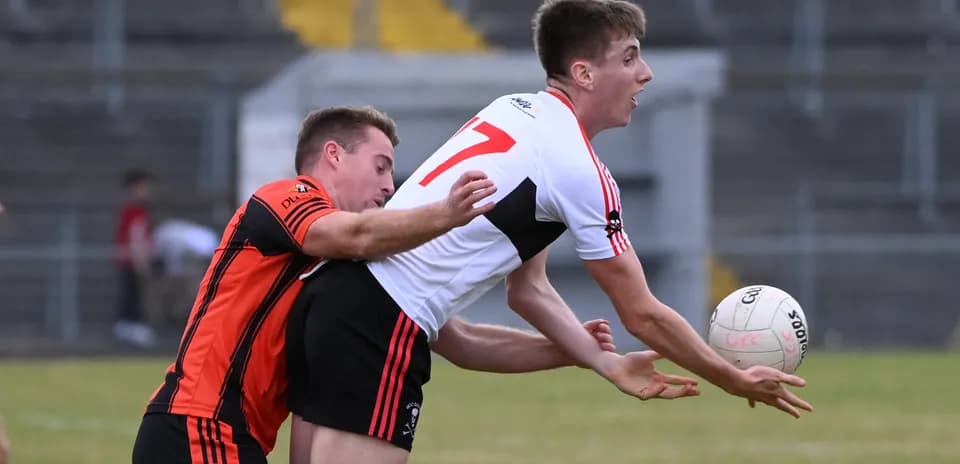 Player catching the ball while being tackled by opponent