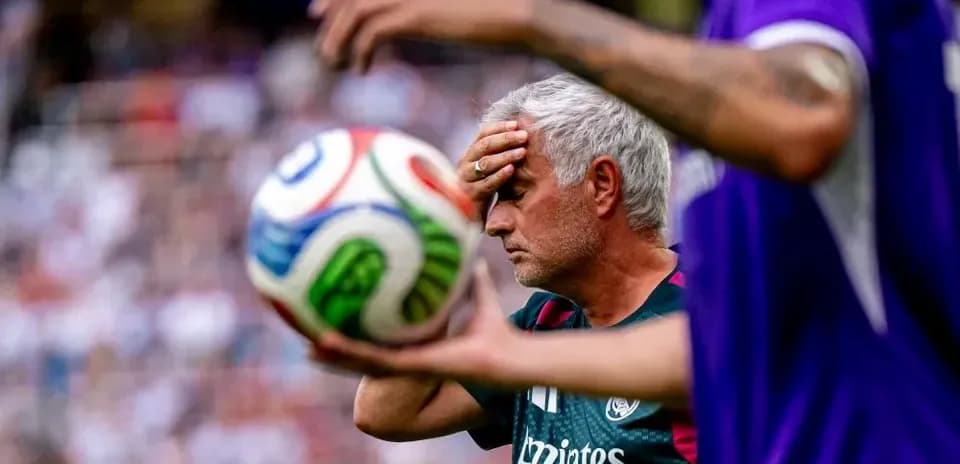 Coach holding head with soccer ball in foreground