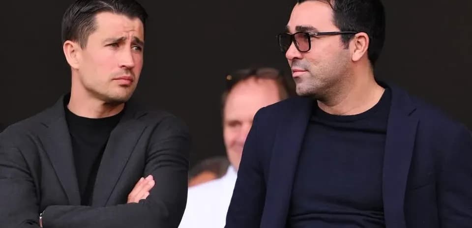 Two men in suits observing from the stands