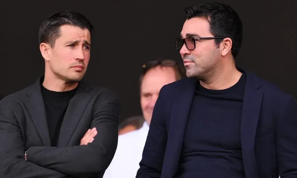Two men in suits observing from the stands