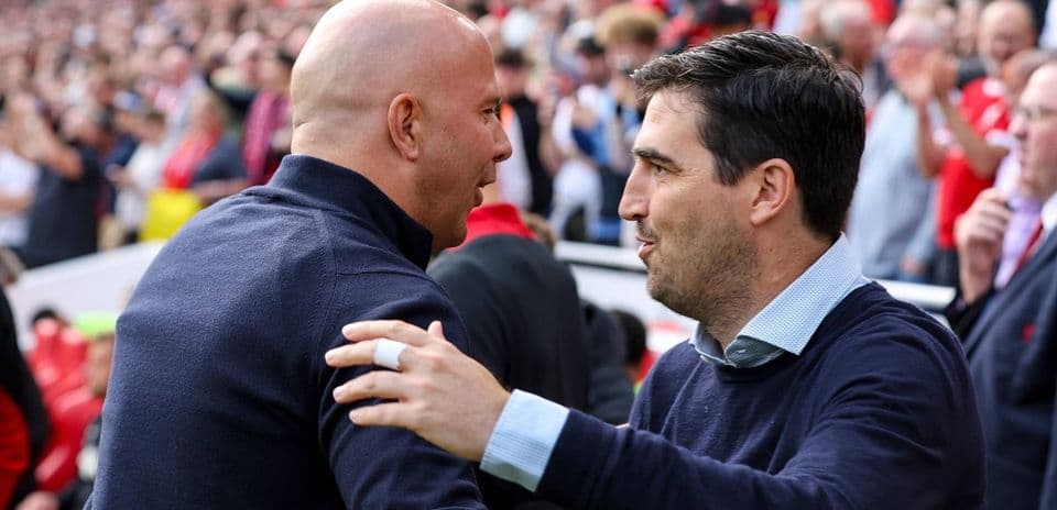 Two coaches greeting each other at a stadium