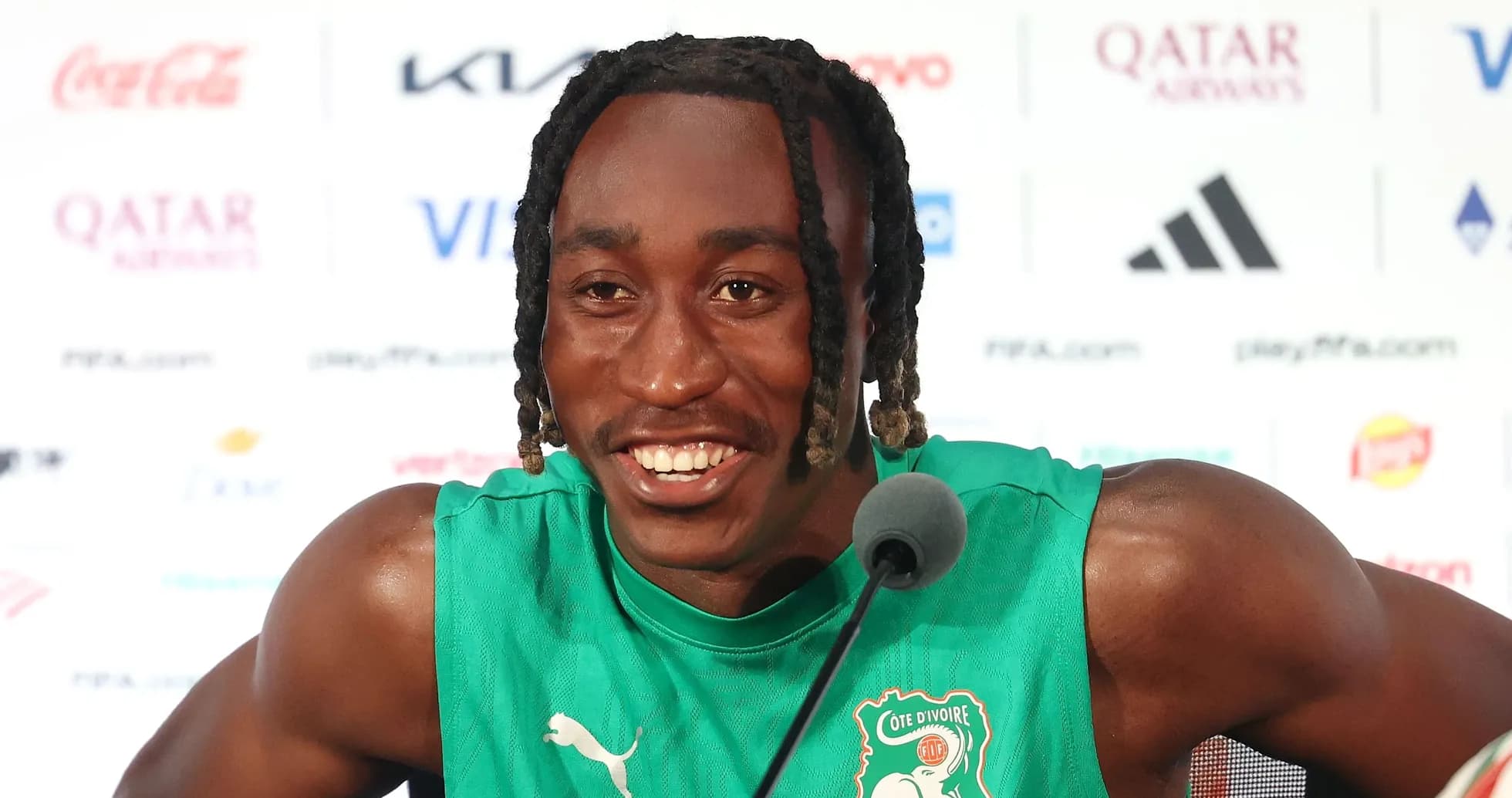 Player speaking at press conference wearing green jersey