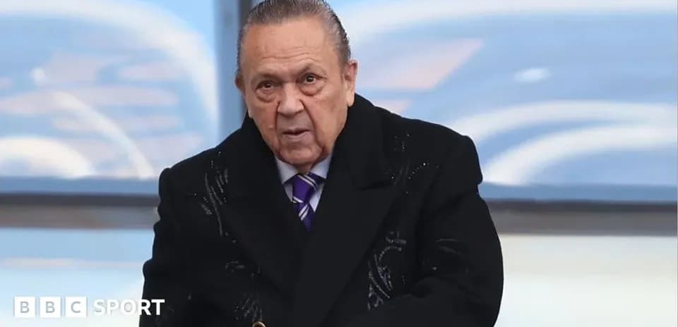Man in black coat at a sports venue