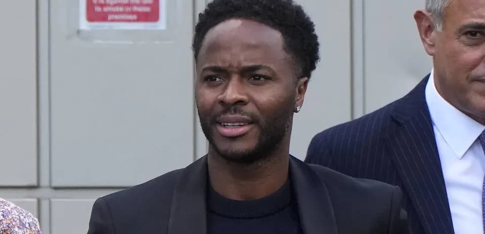 Man in black suit walking with others outdoors