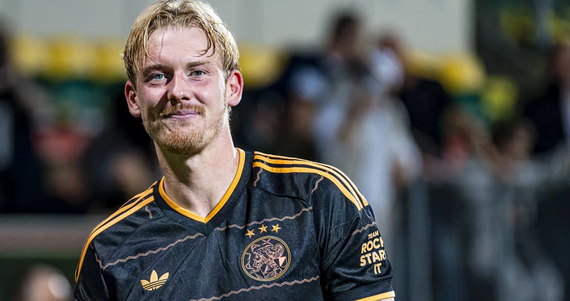 Player smiling in Ajax jersey after match