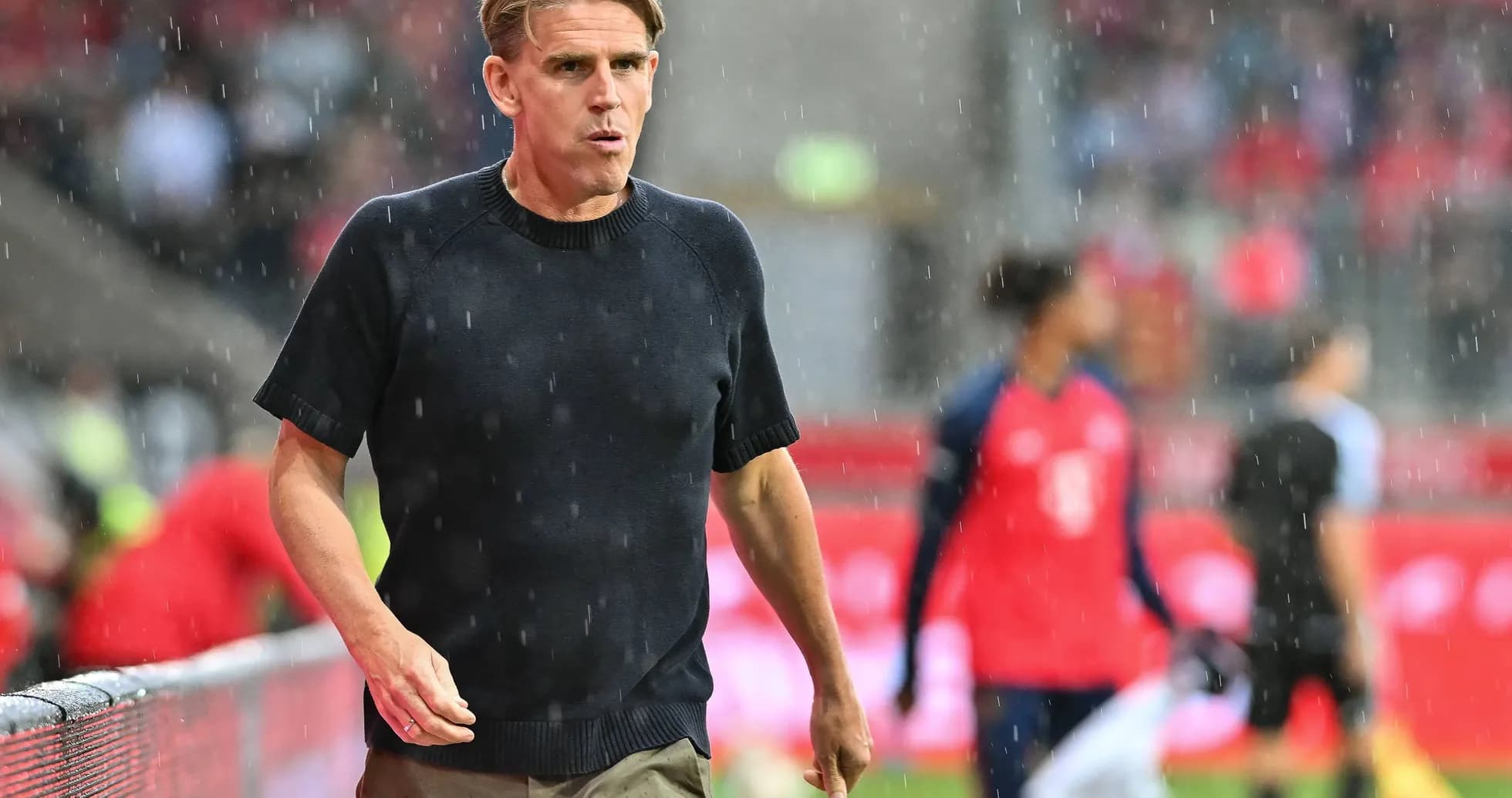 Coach walking along the sideline in rain