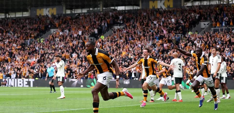 Player celebrating goal with teammates and crowd