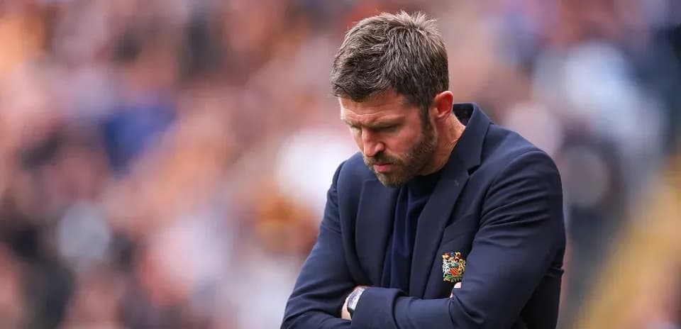 Manager looking down with arms crossed on sideline