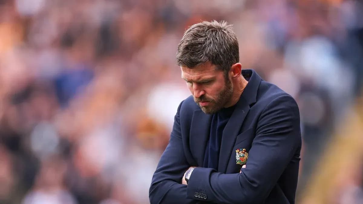 Manager looking down with arms crossed on sideline