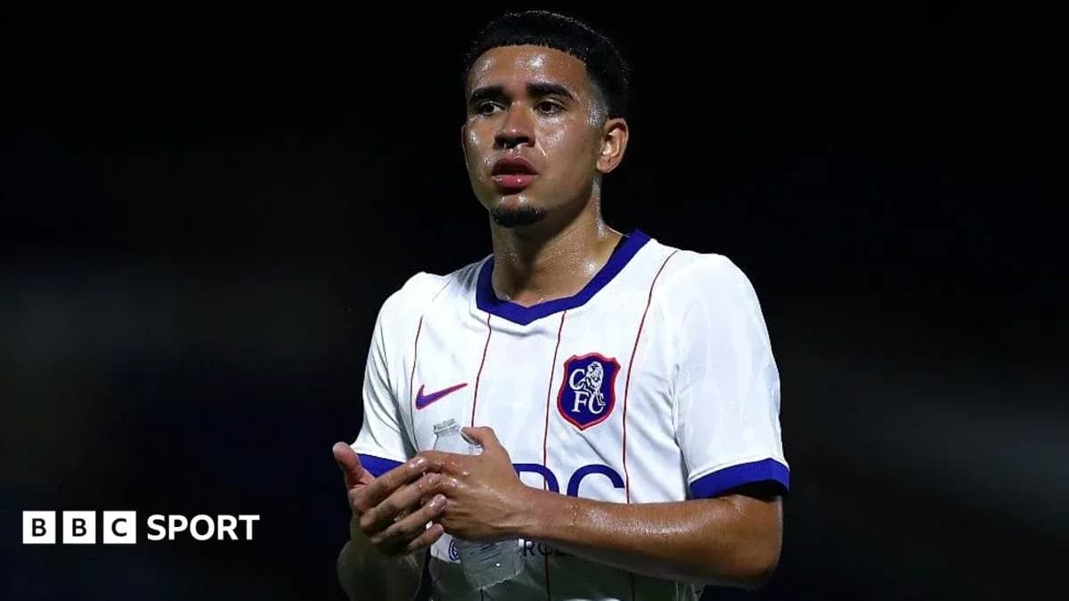 Player in white jersey holding water bottle on pitch