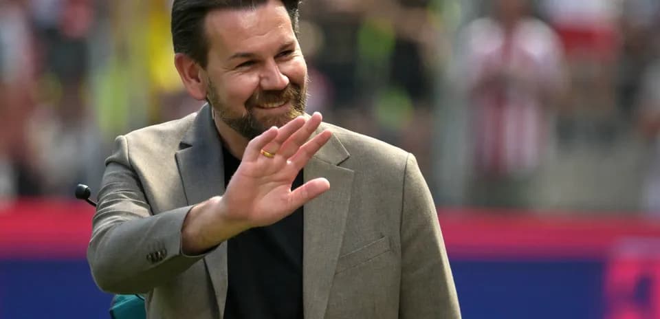 Man in suit waving to the crowd at stadium