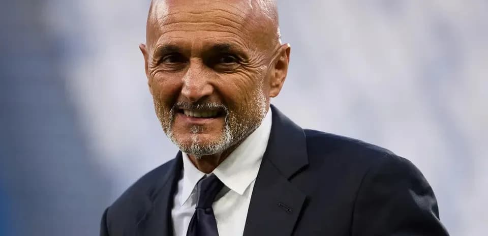 Coach smiling in formal attire on the sidelines