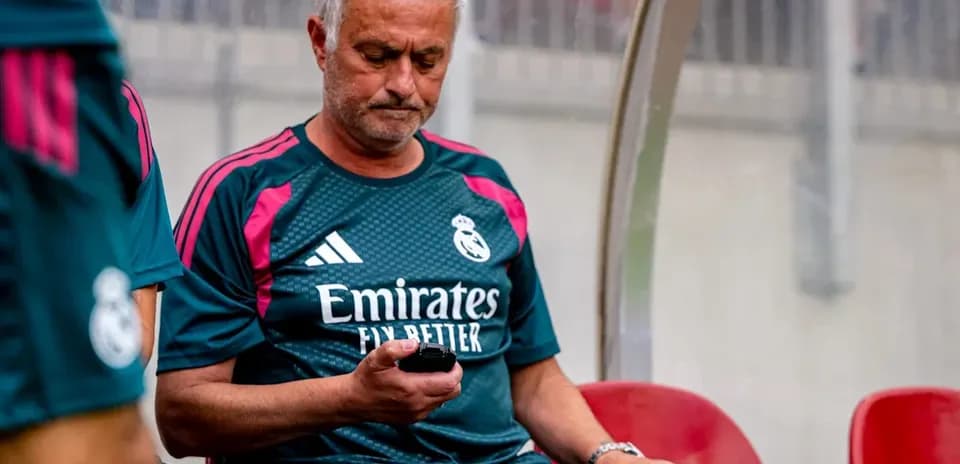 Coach sitting on bench using mobile phone