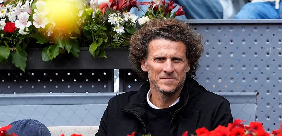Man seated among flowers at a tennis event