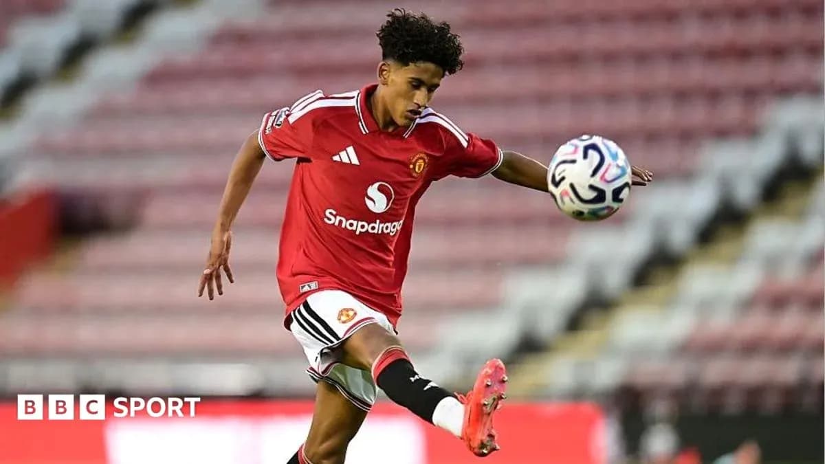Player in Manchester United kit kicking a soccer ball