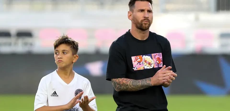 Lionel Messi and a child applauding on the field