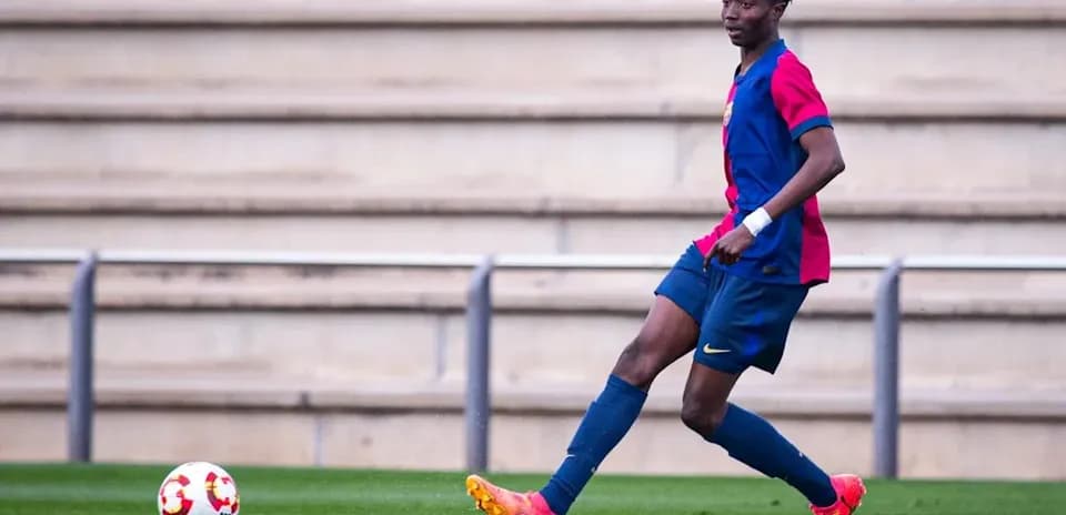 Player in FC Barcelona kit dribbling ball on pitch