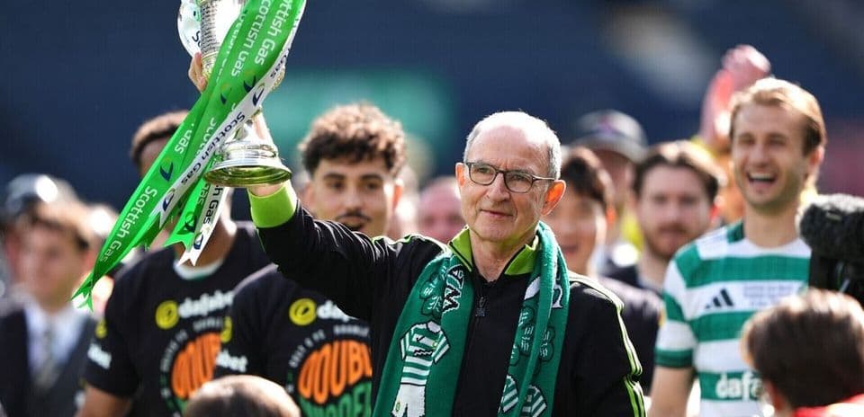 Coach holding trophy with team celebrating behind