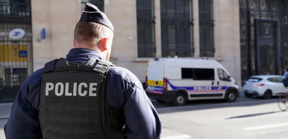 Police officer observing street with police van nearby