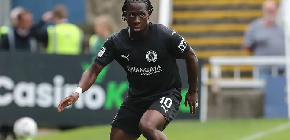 Player in black kit running on the pitch