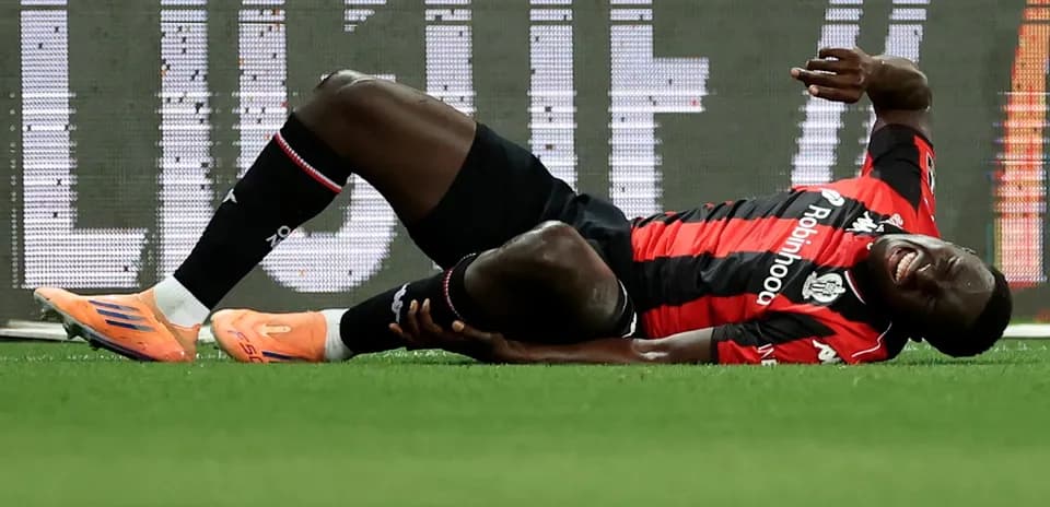 Player lying on ground, holding injured leg