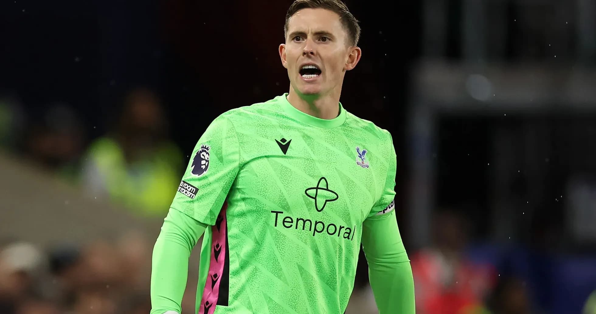 Goalkeeper in green kit shouting on the field