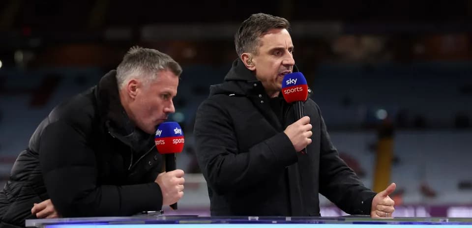 Two sports commentators speaking at a broadcast desk