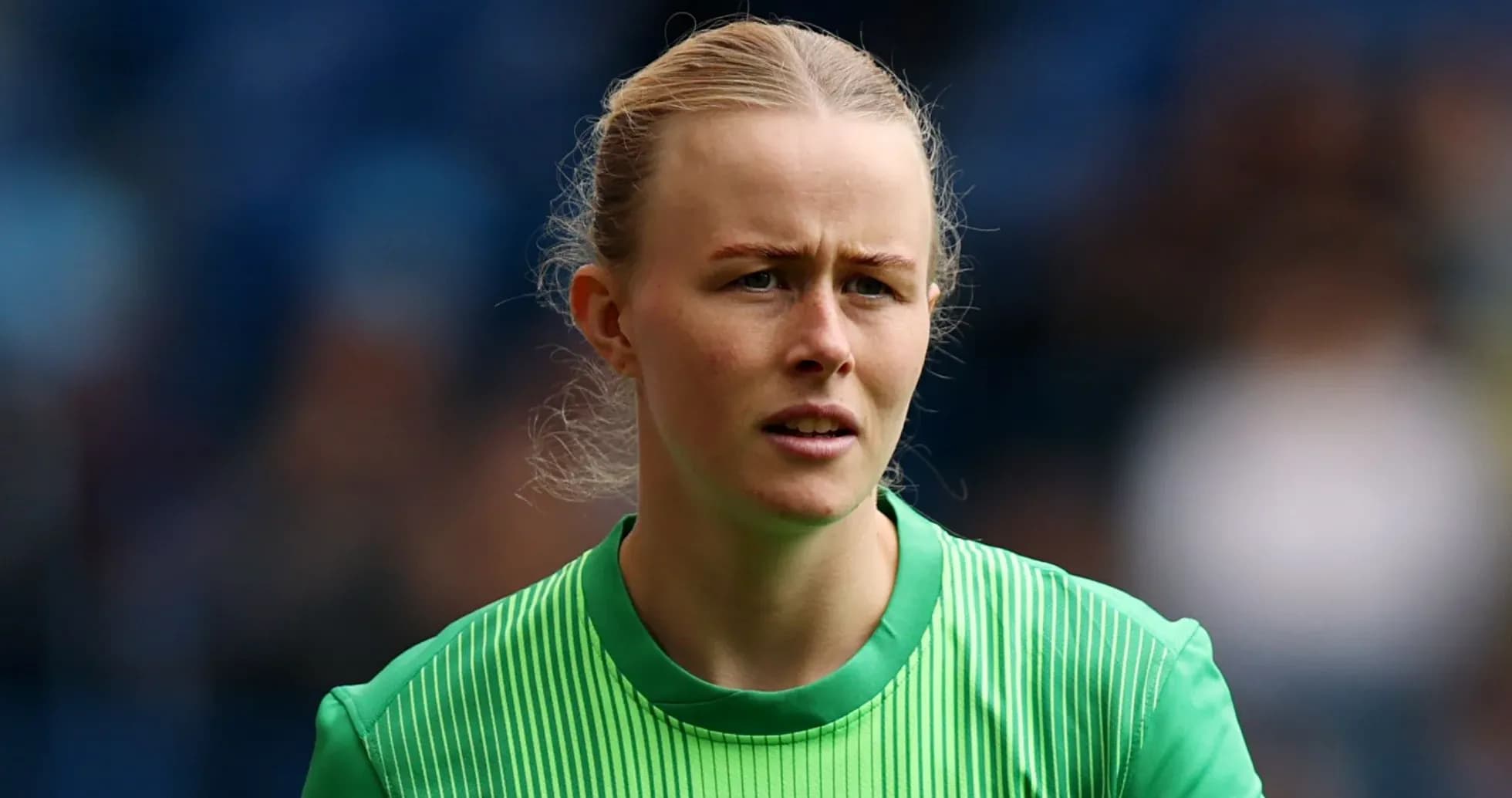 Female goalkeeper in green kit looking focused